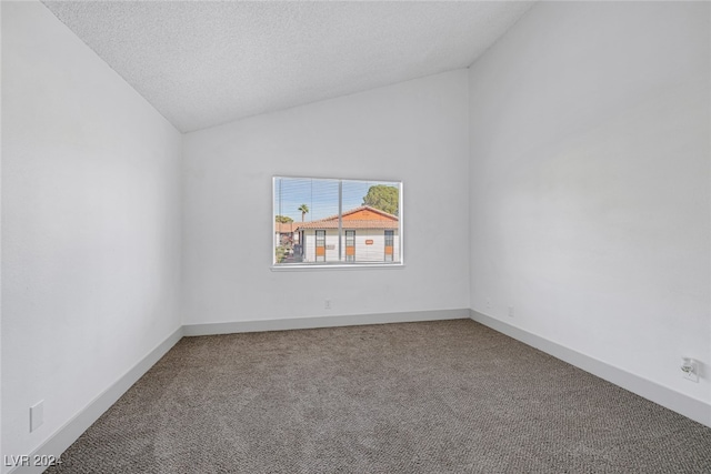 carpeted spare room with a textured ceiling and lofted ceiling