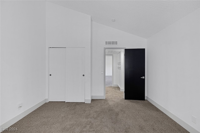 unfurnished bedroom featuring a closet, light carpet, and vaulted ceiling