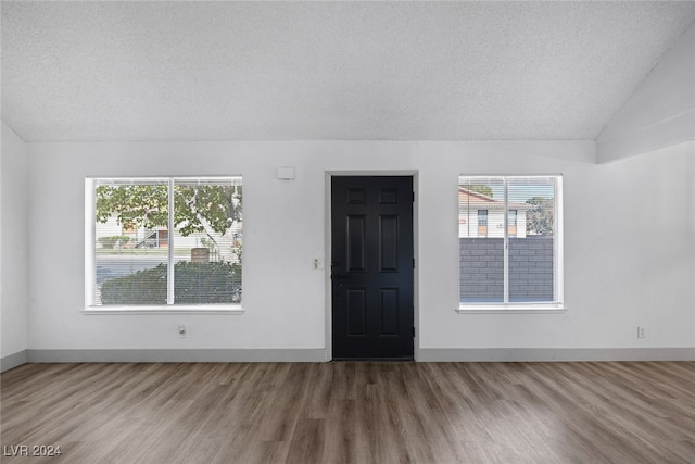 spare room featuring vaulted ceiling, a textured ceiling, and hardwood / wood-style flooring