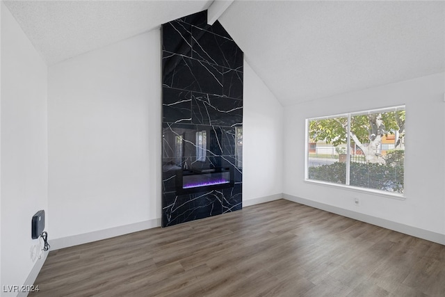 unfurnished living room featuring wood-type flooring, lofted ceiling with beams, a textured ceiling, and a premium fireplace