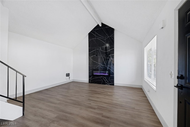 unfurnished living room featuring wood-type flooring, lofted ceiling with beams, and a textured ceiling