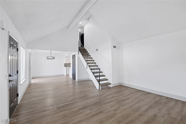 unfurnished living room featuring wood-type flooring, lofted ceiling with beams, a textured ceiling, and a notable chandelier