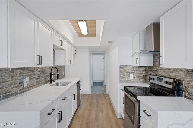 kitchen featuring appliances with stainless steel finishes, light wood-type flooring, sink, wall chimney range hood, and white cabinets