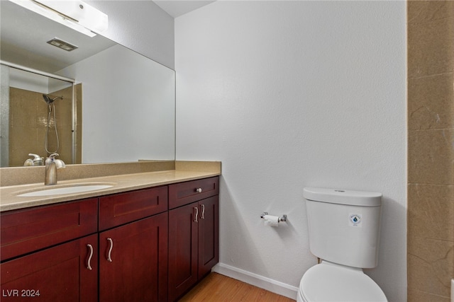 bathroom featuring a shower, hardwood / wood-style floors, vanity, and toilet