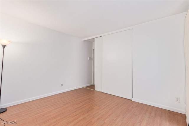 unfurnished bedroom with light wood-type flooring and a closet