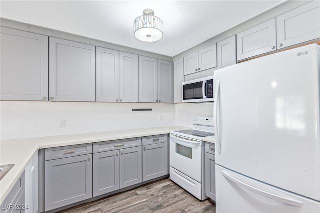 kitchen featuring hardwood / wood-style floors, gray cabinets, and white appliances