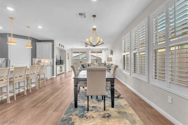 dining area with light hardwood / wood-style flooring and a notable chandelier