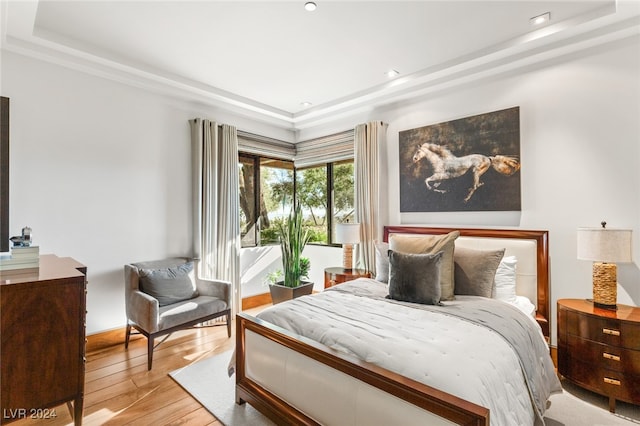 bedroom featuring a raised ceiling and light wood-type flooring