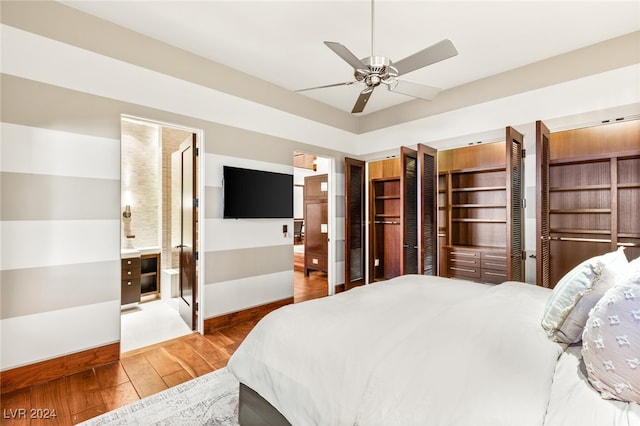 bedroom featuring connected bathroom, multiple closets, hardwood / wood-style floors, and ceiling fan