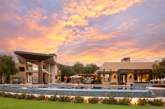 pool at dusk featuring pool water feature