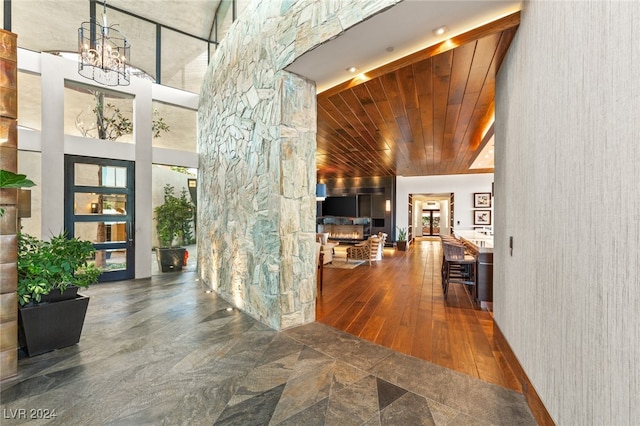 corridor featuring hardwood / wood-style floors, wooden ceiling, a high ceiling, and a notable chandelier