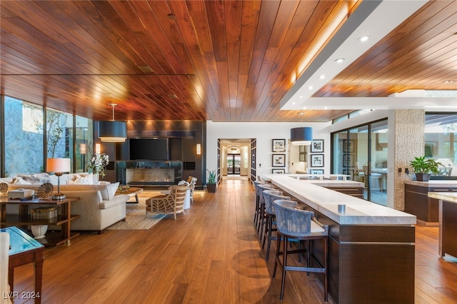 living room featuring light hardwood / wood-style floors, wooden ceiling, and a wealth of natural light