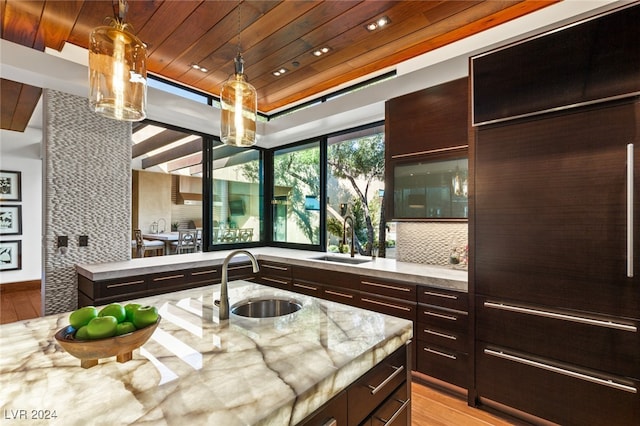 kitchen with light stone countertops, light hardwood / wood-style flooring, and sink