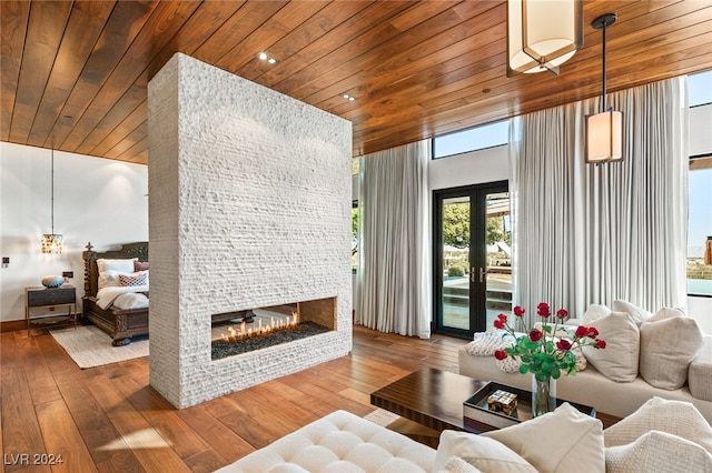 living room featuring hardwood / wood-style floors, wood ceiling, a fireplace, and a towering ceiling