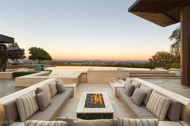 patio terrace at dusk featuring a water view and an outdoor living space with a fire pit