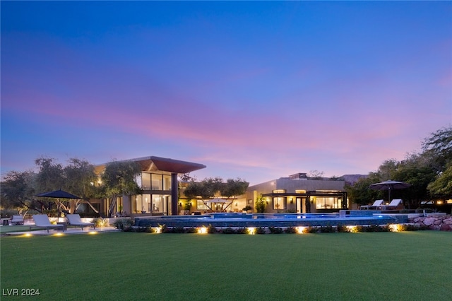 pool at dusk featuring a yard