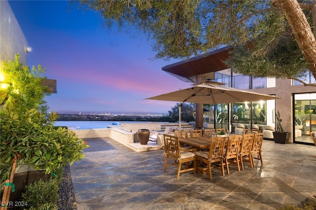 patio terrace at dusk featuring an outdoor living space and a water view