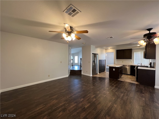 unfurnished living room with hardwood / wood-style floors, ceiling fan, sink, and a textured ceiling