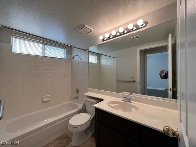 full bathroom with tile patterned floors, a textured ceiling, toilet, vanity, and tiled shower / bath