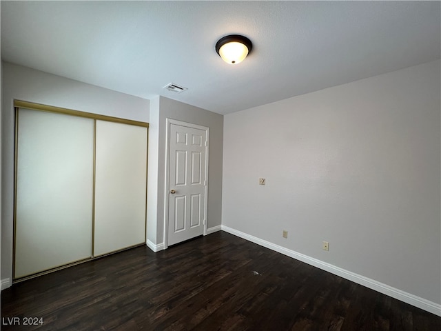 unfurnished bedroom with a closet and dark wood-type flooring