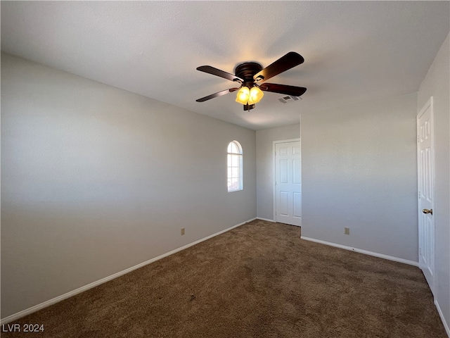 empty room featuring ceiling fan and dark carpet