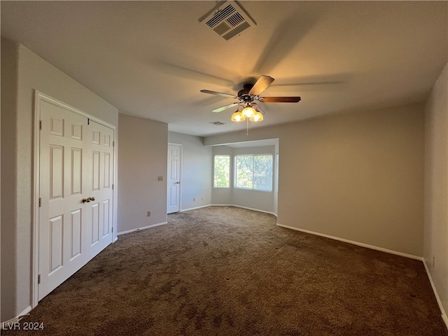 unfurnished bedroom with ceiling fan and dark carpet