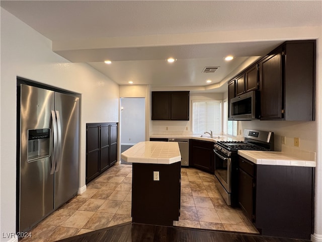 kitchen with tile counters, a center island, sink, and appliances with stainless steel finishes