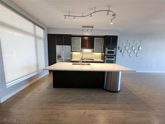 kitchen featuring sink, a center island with sink, light hardwood / wood-style floors, and appliances with stainless steel finishes