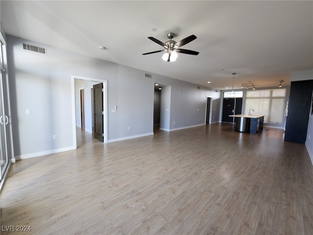 unfurnished living room featuring ceiling fan and hardwood / wood-style flooring