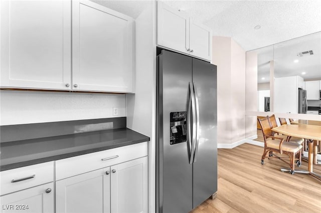 kitchen with white cabinets, light hardwood / wood-style flooring, a textured ceiling, stainless steel fridge with ice dispenser, and stainless steel refrigerator