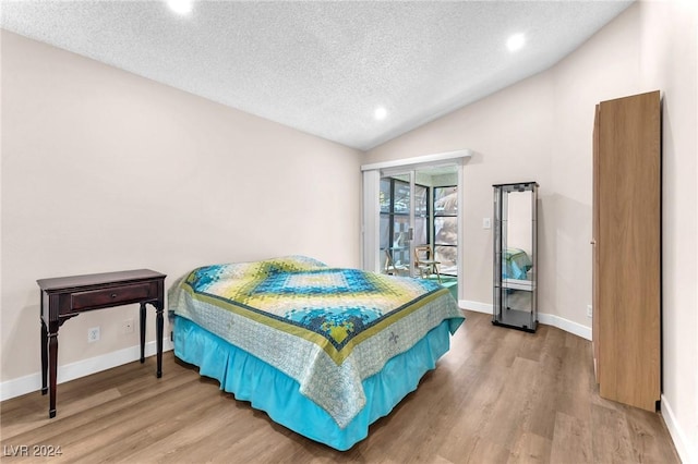 bedroom with lofted ceiling, wood-type flooring, and a textured ceiling