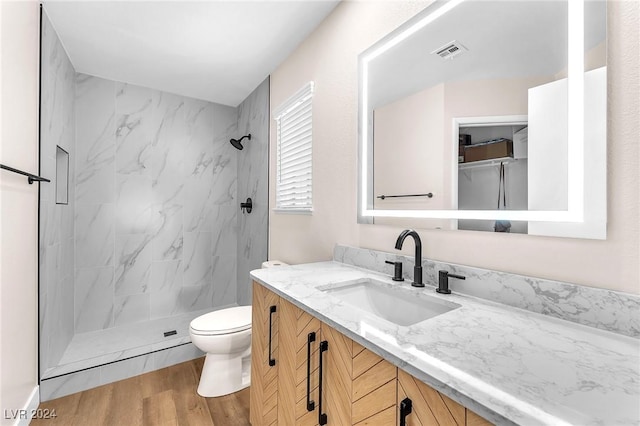 bathroom featuring tiled shower, wood-type flooring, vanity, and toilet