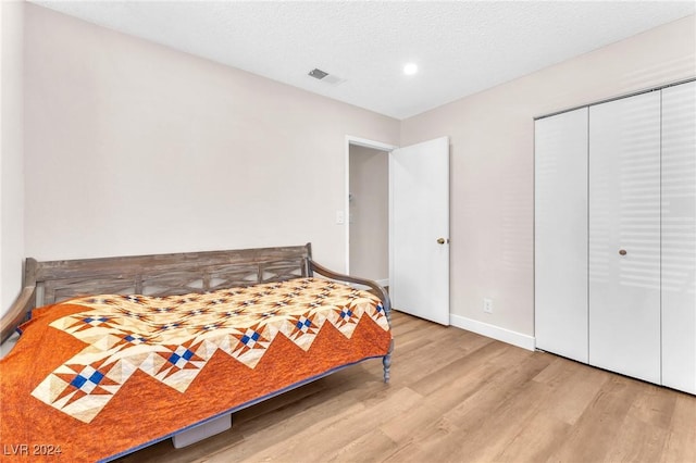 bedroom featuring a textured ceiling, light hardwood / wood-style floors, and a closet