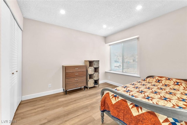 bedroom featuring light wood-type flooring, a textured ceiling, and a closet