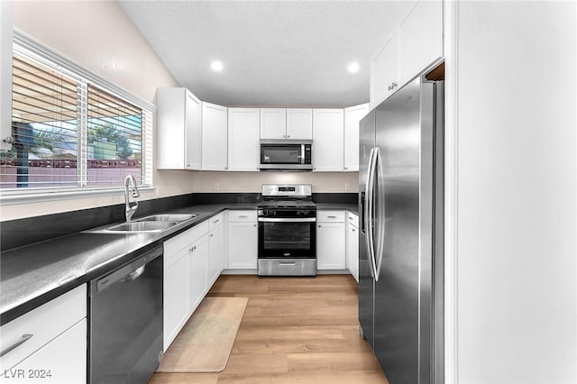 kitchen with sink, stainless steel appliances, light hardwood / wood-style flooring, a textured ceiling, and white cabinets