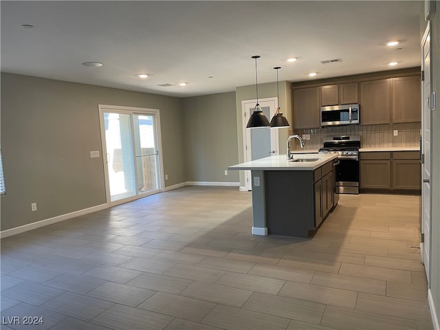 kitchen with decorative backsplash, stainless steel appliances, sink, a center island with sink, and hanging light fixtures