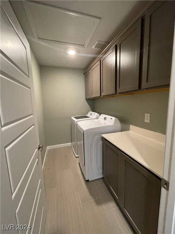 clothes washing area with washing machine and clothes dryer and cabinets