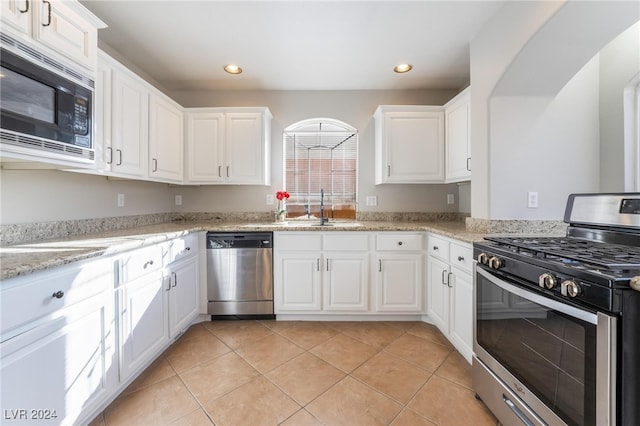 kitchen featuring appliances with stainless steel finishes, light stone counters, white cabinetry, and sink