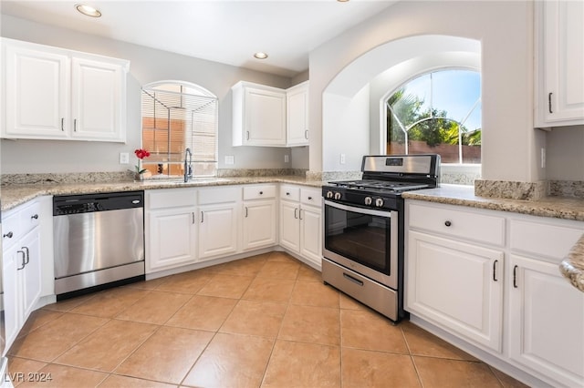 kitchen featuring sink, light stone countertops, light tile patterned flooring, white cabinetry, and stainless steel appliances