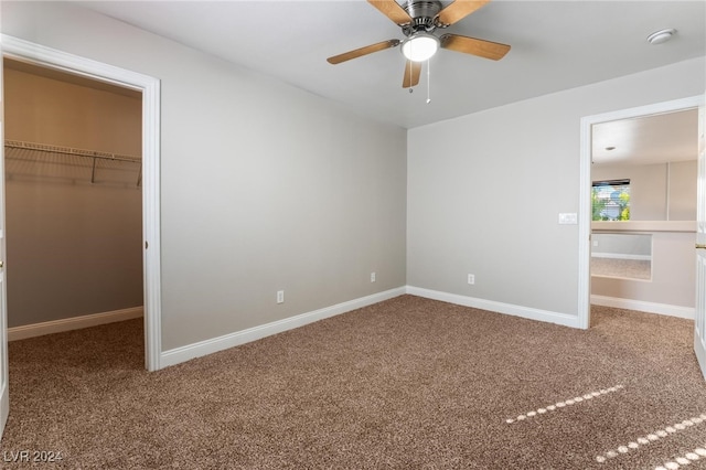 unfurnished bedroom featuring ceiling fan, a spacious closet, carpet floors, and a closet