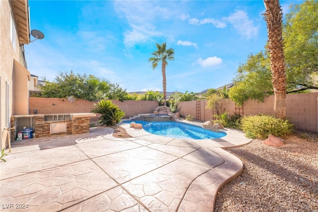 view of pool with exterior kitchen and a patio