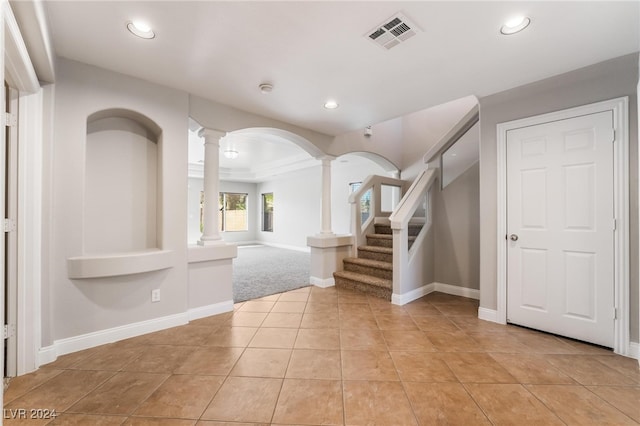 tiled foyer entrance with decorative columns and ornamental molding