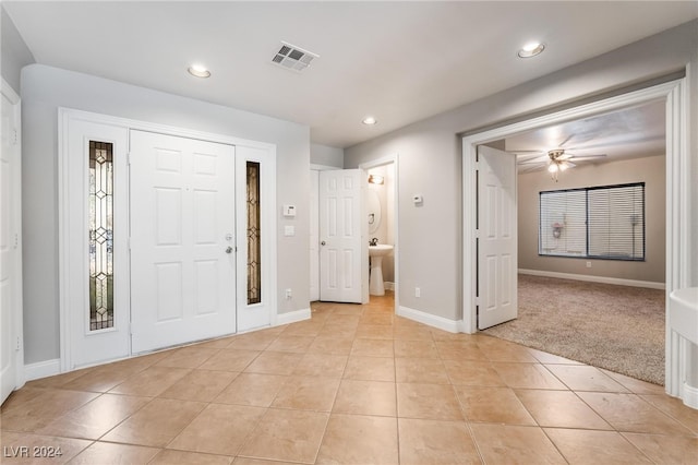 foyer entrance featuring ceiling fan, sink, and light carpet