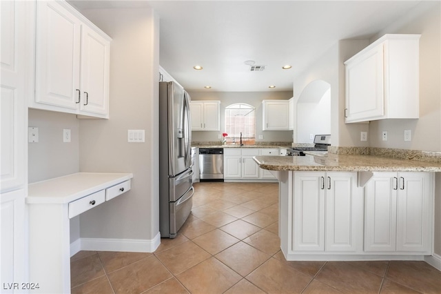 kitchen with kitchen peninsula, light stone counters, white cabinets, and stainless steel appliances