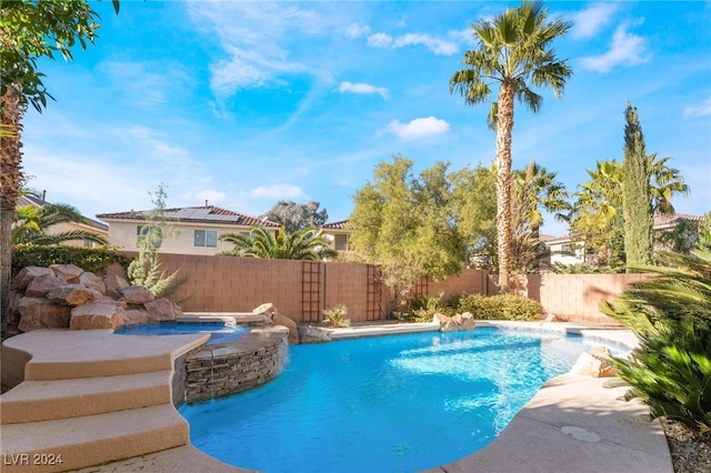 view of swimming pool with pool water feature and an in ground hot tub