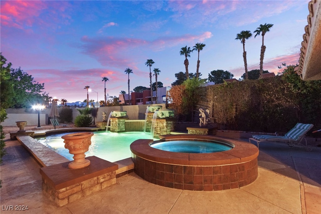 pool at dusk with an in ground hot tub and pool water feature