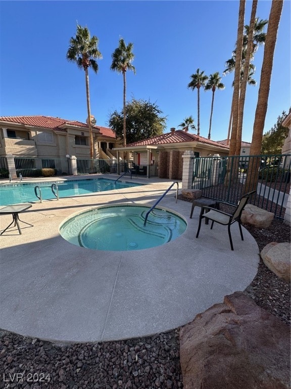 view of swimming pool featuring a patio and a hot tub