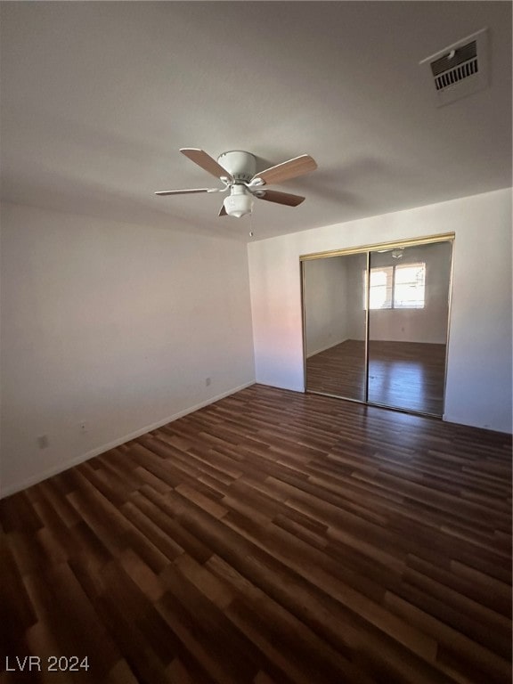 unfurnished bedroom with ceiling fan, dark wood-type flooring, and a closet