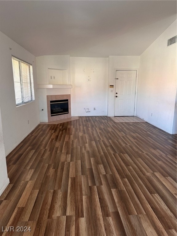 unfurnished living room with dark hardwood / wood-style flooring and a tiled fireplace