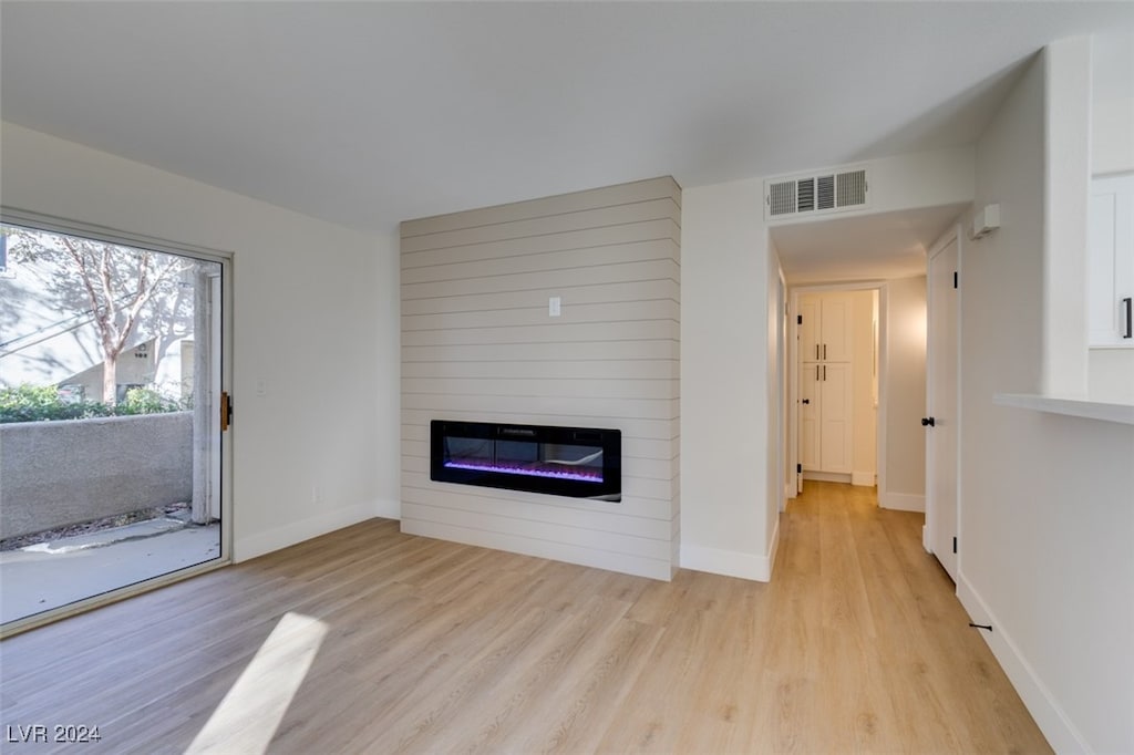 unfurnished living room featuring a large fireplace and light wood-type flooring